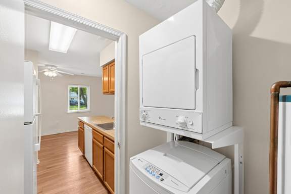 A white dishwasher is in a kitchen with wooden cabinets.