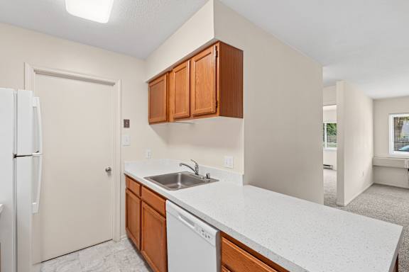A kitchen with white countertops and wooden cabinets.