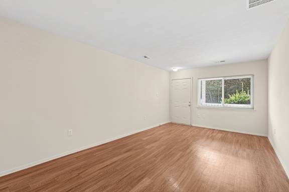 A room with wooden flooring and a window.