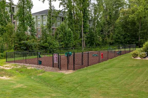 A green lawn with a fence and a sign at Foxwood Apartments, North Carolina