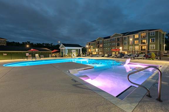A lit up pool at night with a building in the background at Foxwood Apartments, Raleigh-Durham, 27616