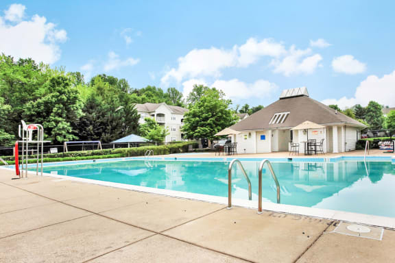 Pool area with tanning chairs on the deck facing leasing office and playground