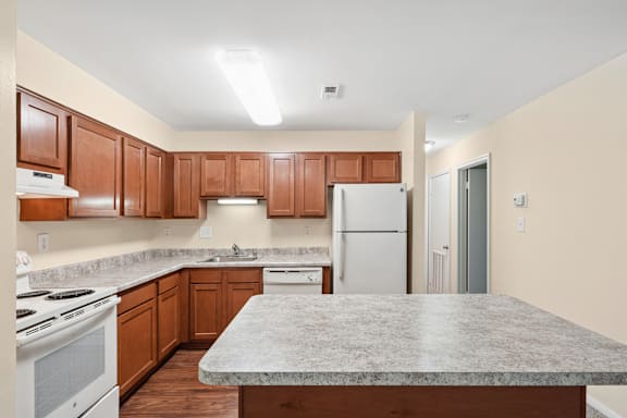 A kitchen with white appliances and wooden cabinets.