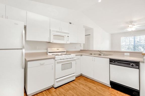 Kitchen with white appliances, wood flooring, gas stove, ceiling fan