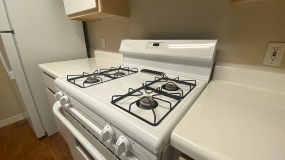Kitchen with white gas stove, white counter tops, white cabinet faces, and white refrigerator