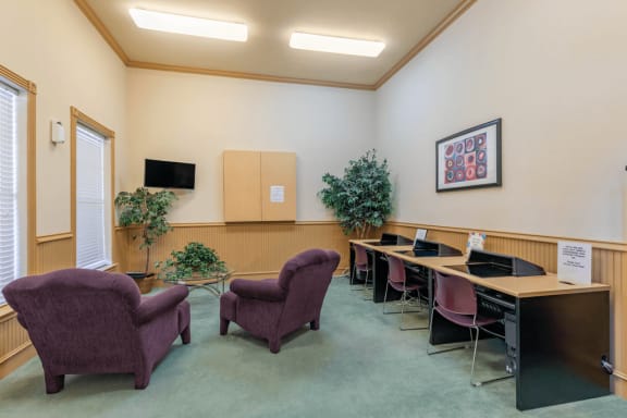 Computer lab with wall mounted television, fabric chairs and indoor plants