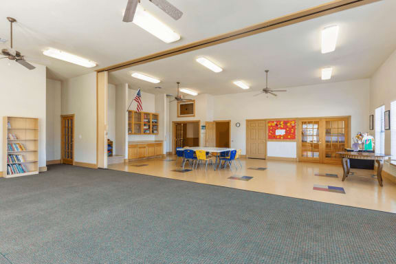 Activity room with tables and chairs, ceiling fan, and tile flooring, sliding partition and carpeted area