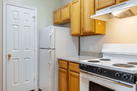 Kitchen with wood cabinetry, white appliances, pantry door