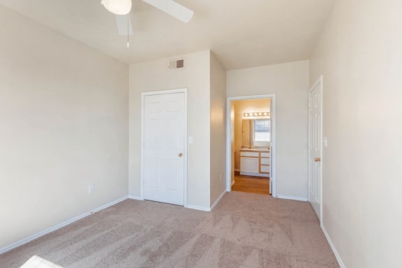 Bedroom carpet, ceiling fan with light, en suite bathroom and door to closet