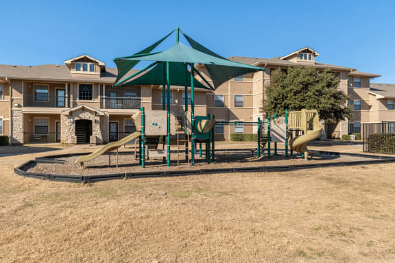 Outdoor playground with slides surrounded by building exterior and native landscape