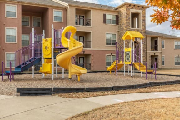 Playground with wood chips in court yard between buildings.