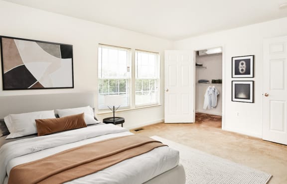 Virtually staged bedroom. Carpeted bedroom with grey and tan accent bed/artwork. Closet in background
