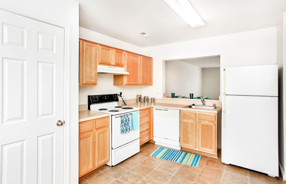 Kitchen with tile floors, white appliances, and wood cabinets.