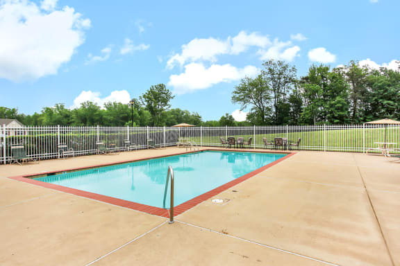 Pool area with outdoor seating. Pool lounge chairs and umbrellas in background