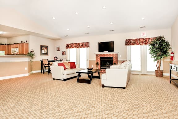 Clubroom seating area. Two couches with coffee table and tv. Clubroom kitchen in background.