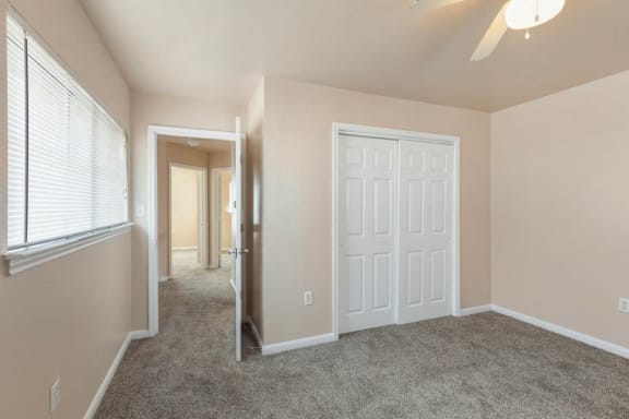 Bedroom with wall to wall carpet, ceiling fan, and closet with french doors