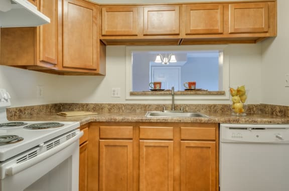 Kitchen with wood cabinets, granite style countertops, and white appliances