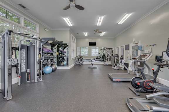 A spacious gym with a variety of equipment and a ceiling fan.