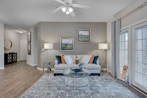 A living room with a white couch and a glass coffee table.