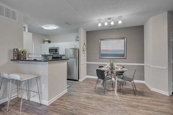 A kitchen with a bar area and a dining table with chairs.