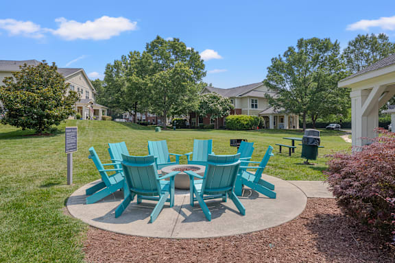 A set of green chairs and a table are arranged in a circle on a concrete slab.