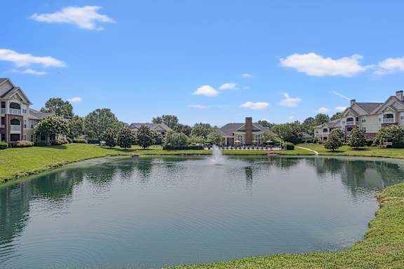 A fountain in the middle of a lake surrounded by apartment buildings..