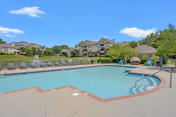 A large swimming pool surrounded by a fence and chairs.