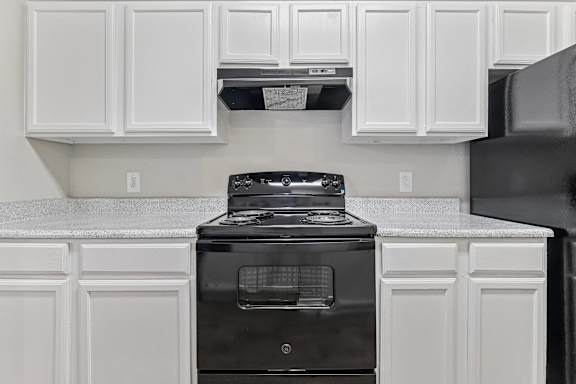 A kitchen with black appliances and white cabinets.