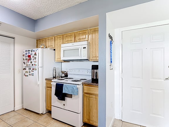 A kitchen with a white refrigerator, white oven, and white microwave.