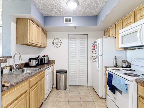 A kitchen with white appliances and wooden cabinets.
