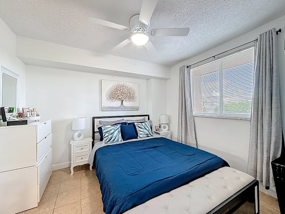 A bedroom with a blue bedspread and white furniture.