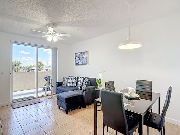A living room with a sliding glass door and a dining table with chairs.