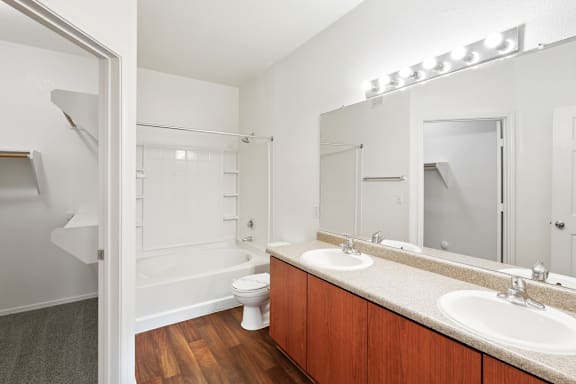 Bathroom with tub shower combo and wood cabinetry at Lake Pleasant Village Apartments, Peoria, Arizona