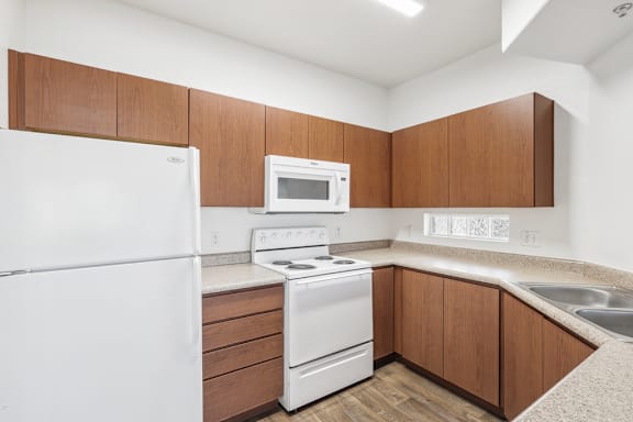 Galley kitchen with speckled countertops and upper cabinetry at Lake Pleasant Village Apartments, Arizona