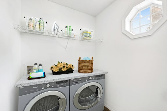 Laundry room area facing  washer and dryer with small exterior window