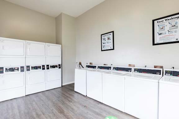 A laundry room with a row of washers and dryers.