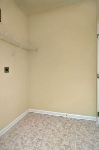 Vacant laundry room with linoleum flooring and wired shelving on the left side of the room.