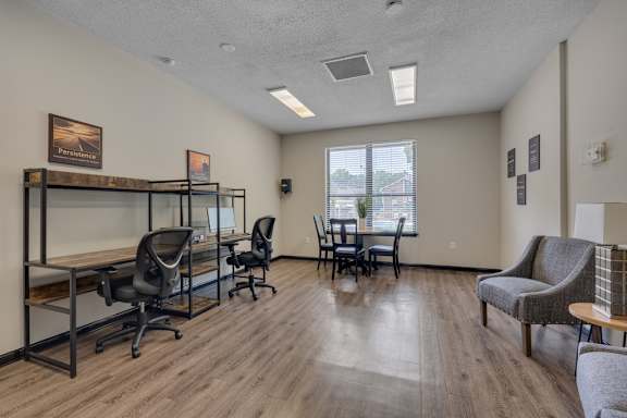 A room with a desk, chairs, and a couch.