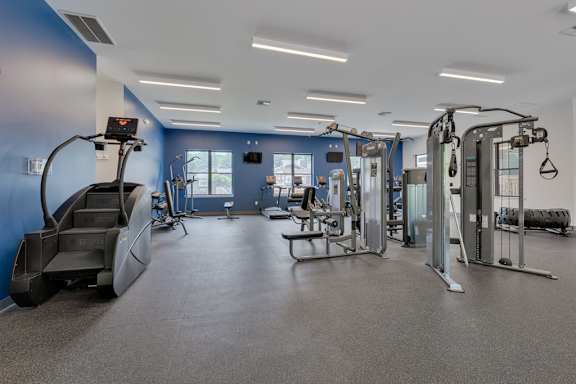A gym with a variety of equipment including treadmills, weights, and exercise machines.