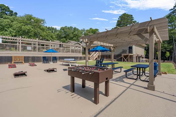 A playground with a shaded picnic table and a swing set.