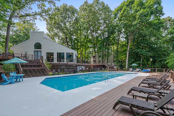 A pool with a deck and resident clubhouse in the background.