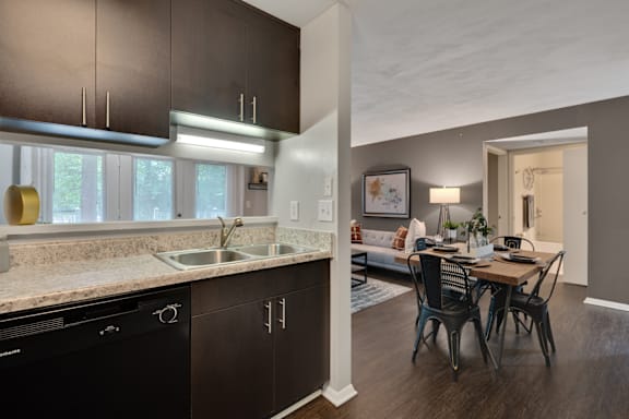 A modern kitchen with dark brown cabinets and a black dishwasher.