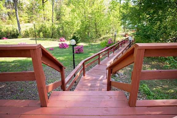 A wooden staircase with railings leads up to a lush green area.