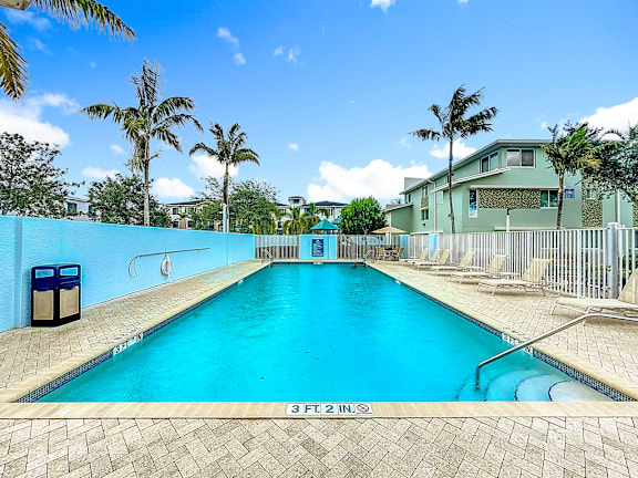 A swimming pool with a blue tiled wall and a diving board.