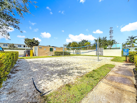 A sunny day at a park with a blue signboard and a yellow building.