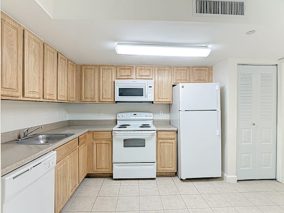 A kitchen with white appliances and wooden cabinets.