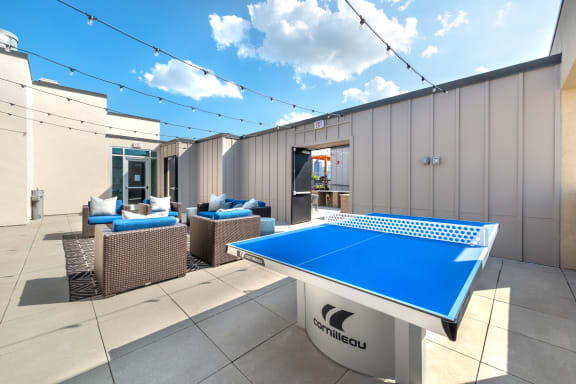Outdoor sitting area next to a ping pong table and grilling area