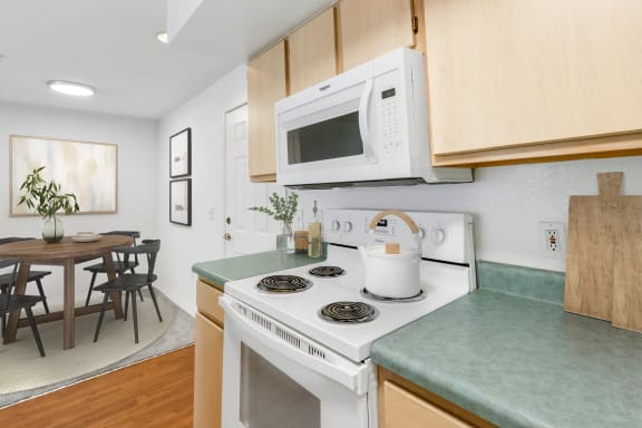 a kitchen with green countertops and a white stove top oven with a white microwave above it