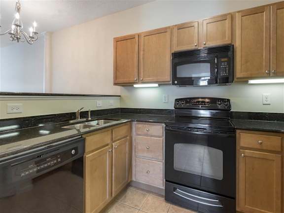 Kitchen with Brown Cabinets Black Appliances and Black Counters and Breakfast Bar