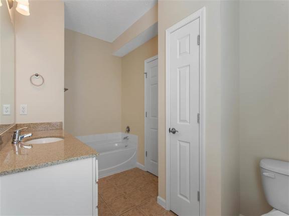 Bathroom with Bathtub Tan Counters White Cabinets and Linen Closet Door